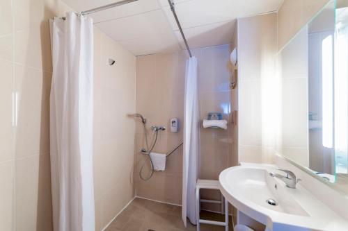 een witte badkamer met een douche en een wastafel bij B&B HOTEL Chalon-Sur-Saone Sud in Saint-Rémy