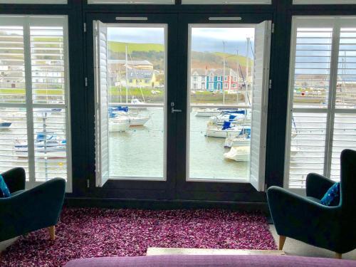 a room with two chairs and windows with boats in the water at Harbourmaster Hotel in Aberaeron