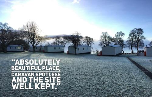 a large field with buildings in the background at Appin Holiday Homes -Caravans, Lodges, Shepherds Hut and Train Carriage stays in Appin
