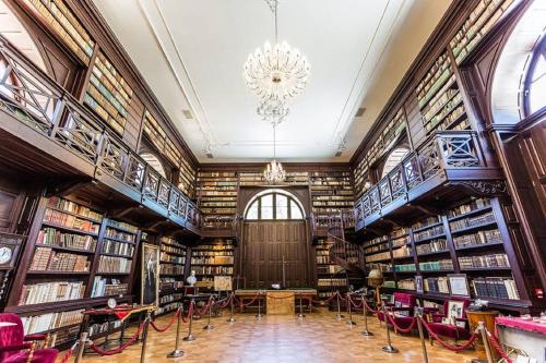 a library with a chandelier and lots of books at Chateau Appony in Oponice