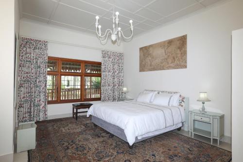 a white bedroom with a bed and a chandelier at Green Olive Guesthouse in Robertson