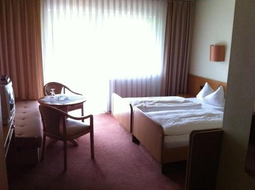 ein Hotelzimmer mit einem Bett, einem Tisch und einem Fenster in der Unterkunft Hotel Bacchusstube garni in Goldbach