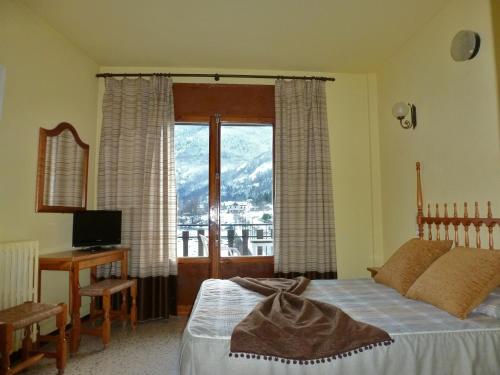 a bedroom with a bed and a desk and a window at Hotel Garona in Bossost