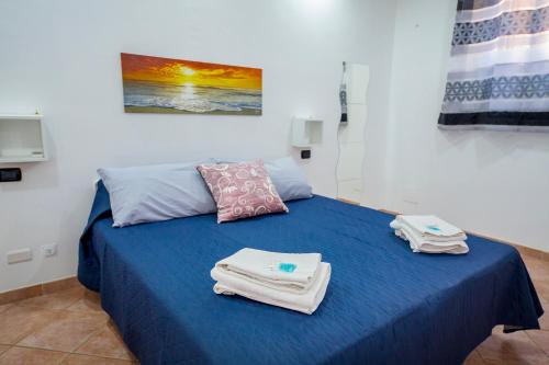 Habitación con cama azul y toallas. en Casa Rubino, en Cefalú