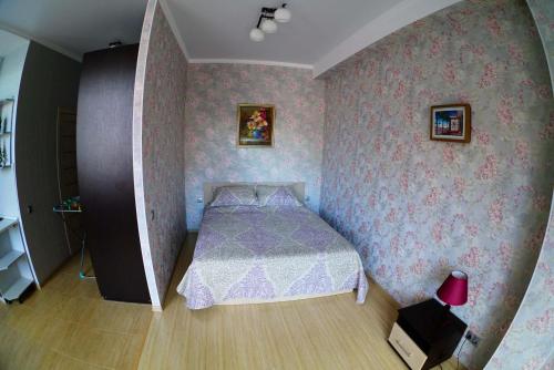アドレルにあるApartment on Yuzhnykh Kultur 10Aのピンクの壁紙のベッドが備わる小さなベッドルーム1室が備わります。