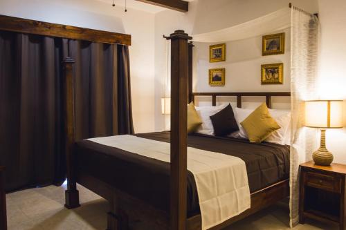 a bedroom with a four poster bed with a canopy at La Leyenda Boutique Hotel by Bunik in Playa del Carmen