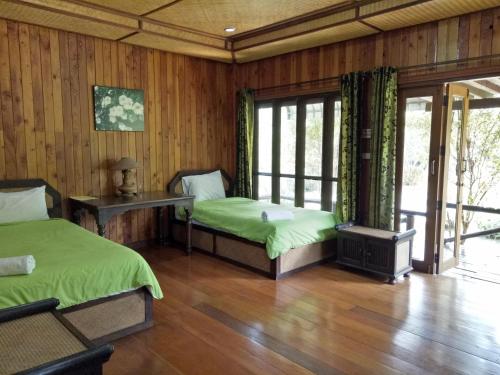 two beds in a room with wooden walls and wood floors at Indie House @ Maerim in Mae Rim