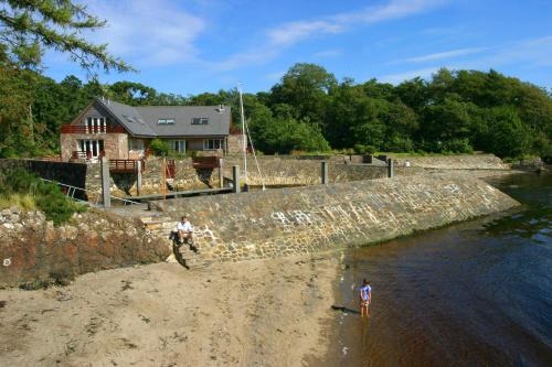 two people standing on the shore of a beach at Melfort Pier & Harbour Resort in Kilmelfort