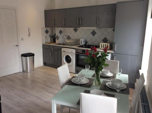 a kitchen with a table with a vase of flowers on it at Rooftop Apartments in Belfast