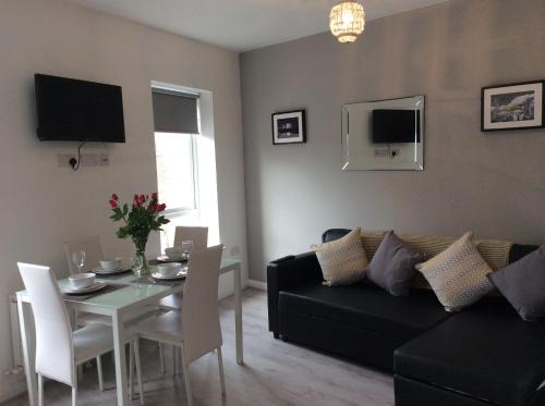 Una sala de estar con un sofá negro y una mesa. en Rooftop Apartments, en Belfast