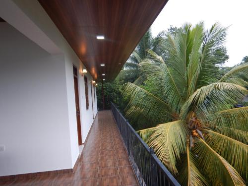 a balcony with a wooden floor and palm trees at Suwani Pinnawala Homestay in Pinnawala