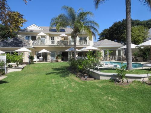a large house with a swimming pool and palm trees at Constantia Valley Lodge in Cape Town