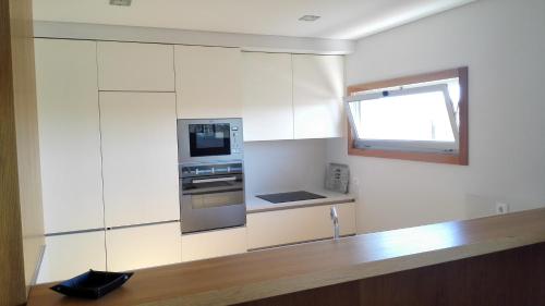 エシュポゼンデにあるT2 Dunas Esposendeの白いキャビネットと窓付きのキッチン