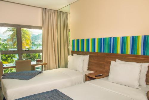 a hotel room with two beds and a window at Prodigy Santos Dumont by Wish in Rio de Janeiro