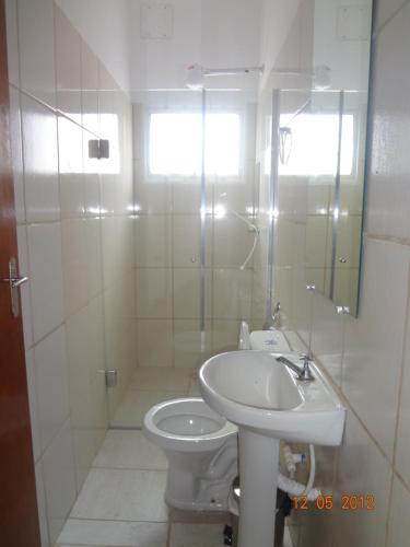 a white bathroom with a toilet and a sink at Hotel Ox Inn in Uberaba