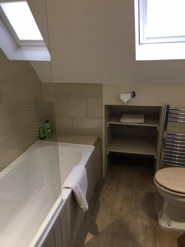 a white bathroom with a tub and a toilet at Far Hill Cottage in Wyck Rissington