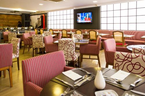 a dining room with tables and chairs and a tv at Mercure Sao Paulo Alamedas in Sao Paulo