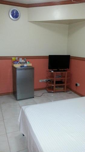 a room with a bed and a tv and a desk at Kokomos Hotel and Restaurant in Angeles