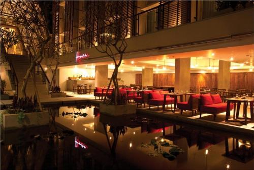 a restaurant with tables and red chairs next to a pool at Ananta Legian Hotel in Legian