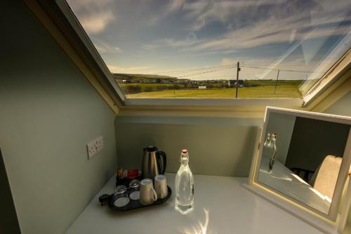 una habitación con ventana y una botella en un mostrador en The Pipers Rest, en Doolin