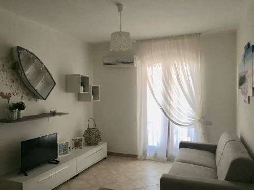 een woonkamer met een bank, een tv en een raam bij Renabianca house in Santa Teresa Gallura