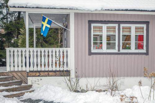 a flag on the front of a house with snow at Comfortable Cottage at Scenic Lake in Landvetter