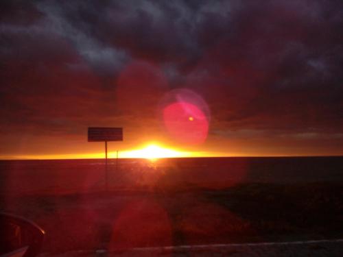a sunset over the ocean with a sign in the foreground at Giorgos Apartments Sea View in Olympiaki Akti