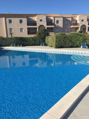 une piscine bleue en face d'un bâtiment dans l'établissement L'Ecume, à Saint-Cyprien