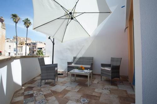 un patio con mesa, sillas y sombrilla en Coraje Room & Breakfast, en Sciacca