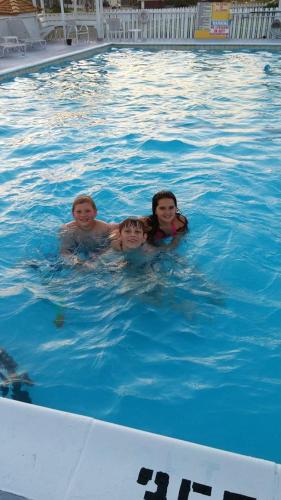 three people are swimming in a swimming pool at Outer Banks Motor Lodge in Kill Devil Hills