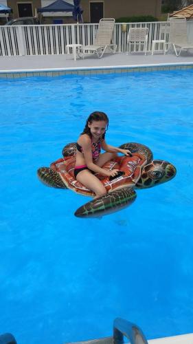 a girl is sitting on an inflatableigator in a swimming pool at Outer Banks Motor Lodge in Kill Devil Hills
