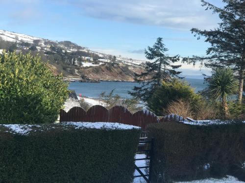 a garden with a fence and a view of the water at Ballymacdoe Cottage Cushendall in Cushendall