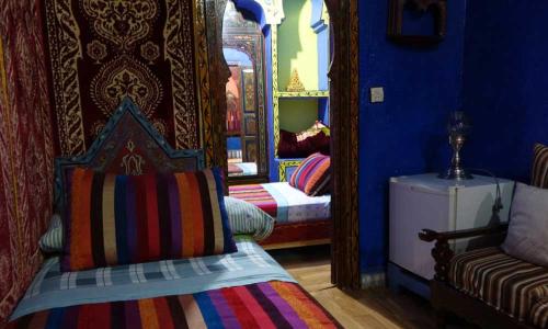 Habitación colorida con cama y espejo. en Dar Antonio, en Chefchaouen