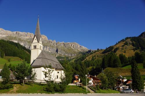 a small white church with a steeple on a mountain at Residence Baita Antlia in Arabba