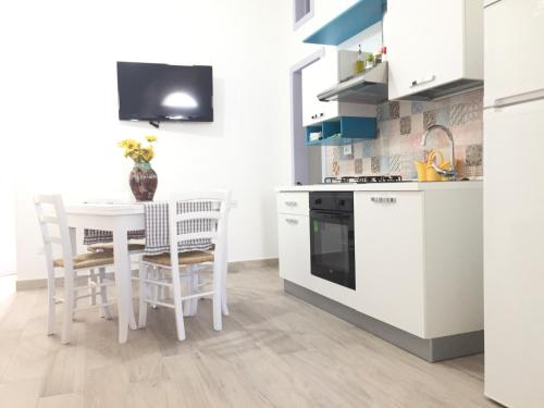 スペッキアにあるLa casa di Andreaの白いキャビネット、テーブルと椅子付きのキッチンが備わります。