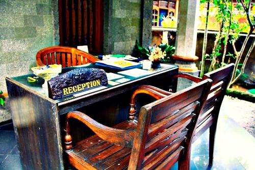 a table with two chairs and a sign on it at Nakula Guest House in Kuta