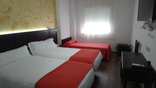Habitación de hotel con 2 camas y ventana en Hotel Restaurante Sostenible La Laguna, en Brozas