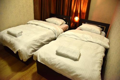 two beds in a hotel room with white blankets at Aden Apartments in Tbilisi City