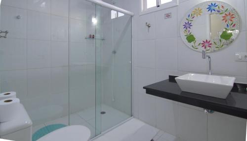 a bathroom with a glass shower and a sink at Pousada Irashai in Juquei