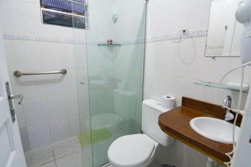 a bathroom with a shower and a toilet and a sink at Pousada Irashai in Juquei