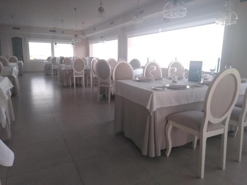 a dining room with white tables and white chairs at Punta Carnero Hostal in Algeciras