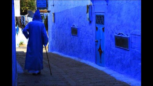 a woman in a blue robe walking down a street at Dar Antonio in Chefchaouene