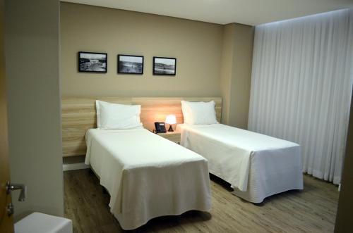 a hotel room with two beds with white sheets at Ville Celestine Hotel in Belo Horizonte