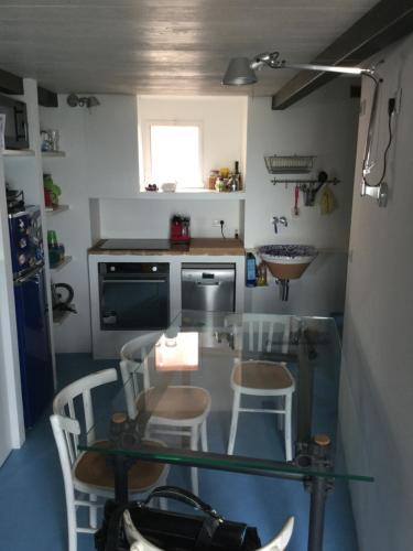 una piccola cucina con tavolo in vetro e sedie di La finestra sul mare a Grottammare