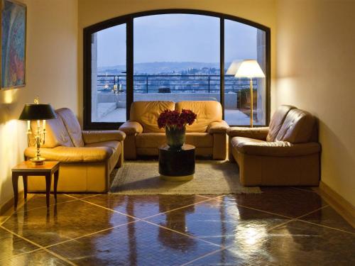 a living room with couches and a large window at Dan Jerusalem Hotel in Jerusalem