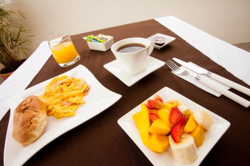- une table avec deux assiettes de produits pour le petit-déjeuner et une tasse de café dans l'établissement Hotel Cafe y Miel, à Pasto