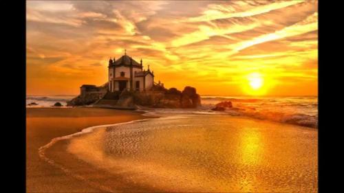 a picture of a lighthouse on the beach at sunset at Oporto Beach in Gulpilhares
