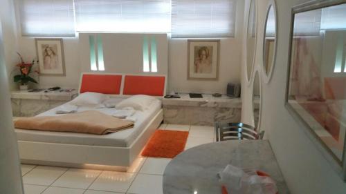 Dormitorio pequeño con cama y mesa en Heru's Motel en Poços de Caldas