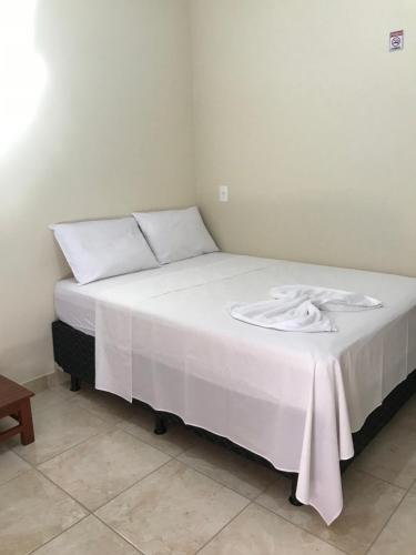 a bed with a white blanket on top of it at Pousada Pouso Vitoria in Pirenópolis