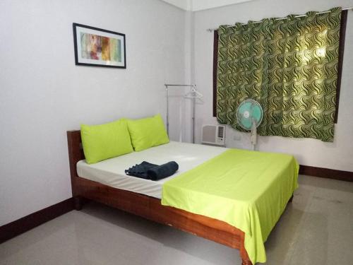 a small bedroom with a bed with a green blanket at Ahras Place in Coron